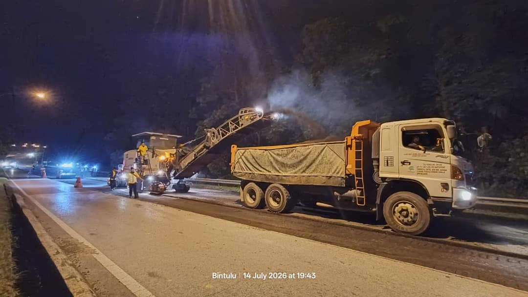 Milling machine loading the removed surface into a tipper truck at night